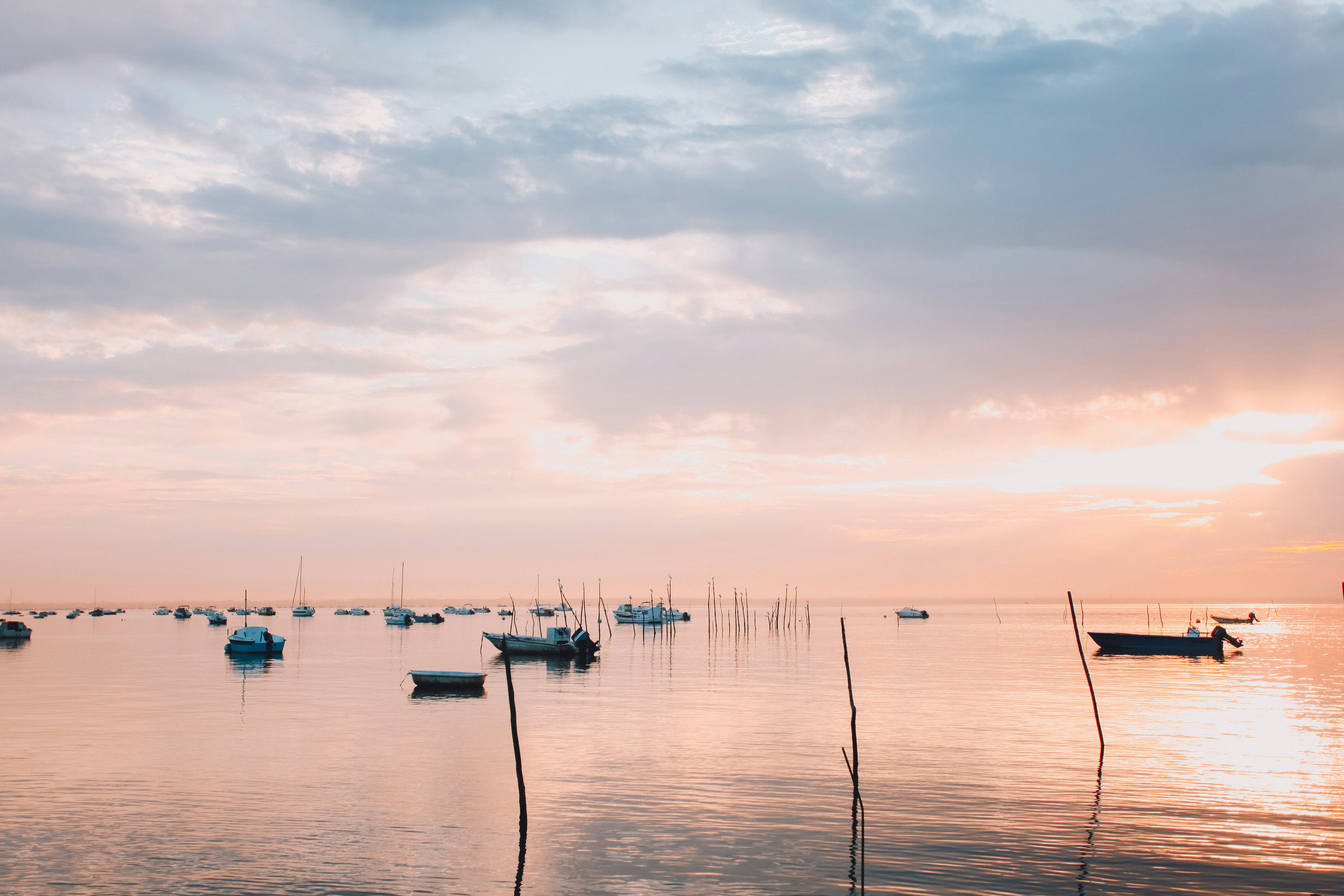 boats anchored at sea during cloudy sunset